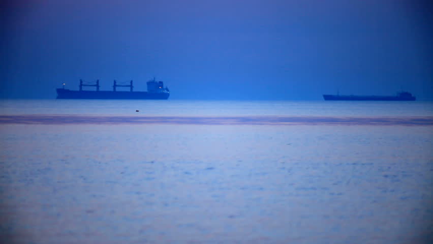 Two cargo ship in the distance at sunset