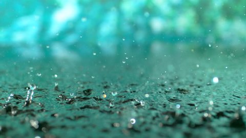 Heavy rain in puddle with green background. Shot with high speed camera, phantom flex 4K. 4K 30fps. Slow Motion.