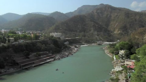 A panning shot of the Rishikesh Valley and the Lakshman Jhula iron suspension bridge across the River Ganges in the holy city of Rishikesh, North India.