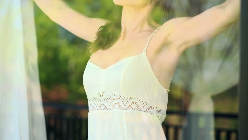 Happy woman unveil curtains, enjoying morning by the window
