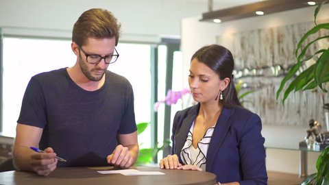 bank assistant helping client to fill out money transfer check
