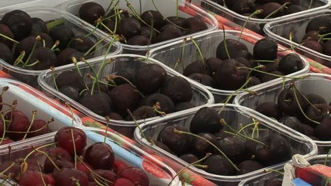 BETUWE, THE NETHERLANDS - MAY 2014: punnet of cherries  + zoom out cherry display at roadside fruit market.During the fruit growing season, they offer a variety of  fruit from the traditional orchard