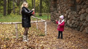 SAINT-PETERSBURG, RUSSIA-October 12, 2014: Mom and daughter blow bubbles in the park on a background of yellow foliage, park Pavlovsk, Saint-Petersburg, Russia  - Powered by Shutterstock - Get 15% off with code: PIKWIZARD15