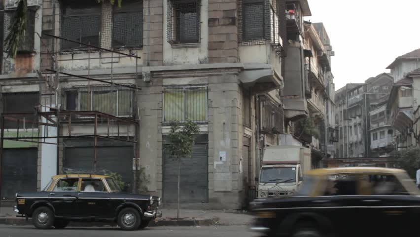 Quiet alleyway in Mumbai India with parked taxi cab and locals walking by