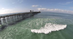 Aerial video of the Oceanside Pier extending into the Pacific Ocean in California on a sunny Autumn afternoon.