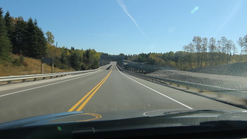 POV driving across a long truss bridge that crosses the Pic River. Footbridge on left and bridge under construction on right. Trans Canada HWY No 1 or Hwy ON-17 in Northern Ontario, Canada.
