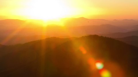Time Lapse of the sun rising from behind mountains. Tight shot with a beautiful lens flare moves through frame.