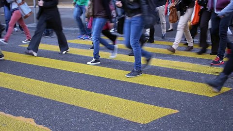 Legs of people crossing zebra crosswalk.  People crossing a street in Zurich, Switzerland during the morning rush hour. 
