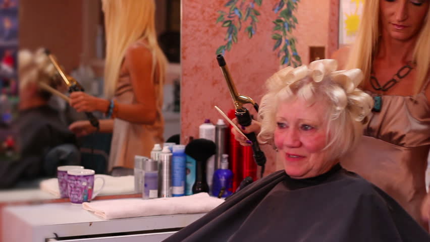 A hairstylist cuts and sets her customer's hair.