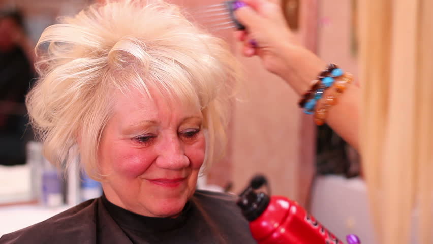 A hairstylist cuts and sets her customer's hair.