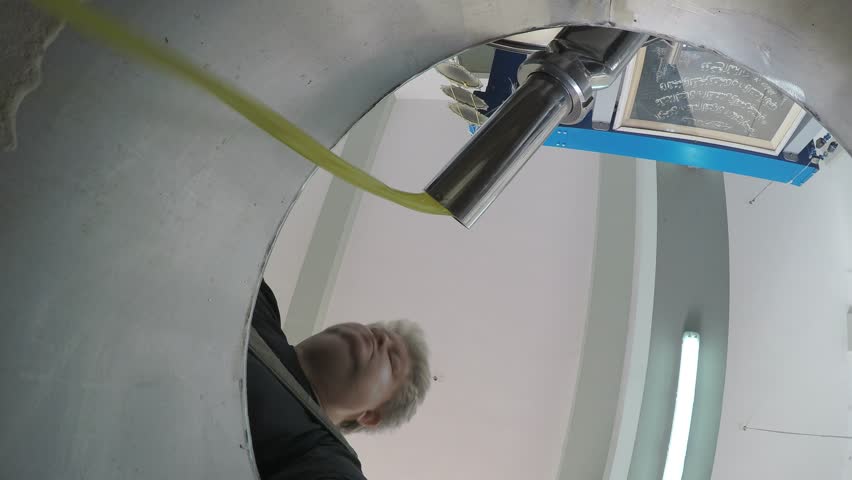 A man looks at olive oil that comes from the pressing machine