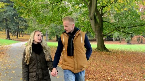 young model couple in love - autumn park(nature) - couple (man and woman) walking in park - couple holding hands - couple talking - happy couple - steadicam