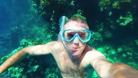 Man swimming underwater, snorkeling, apnea diving near coral reef and holding GoPro, Go Pro, Go-Pro video camera in Marsa Alam, Red Sea, Egypt. Ocean, summer fun, recreation, holidays, water sports