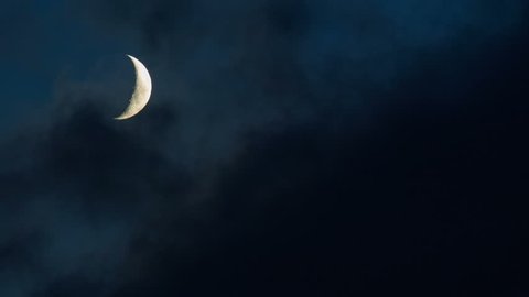 Bright crescent moon moving through wispy clouds, time lapse 4k