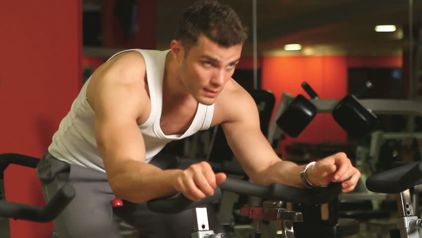 Handsome sporty man is exercising in gym centre