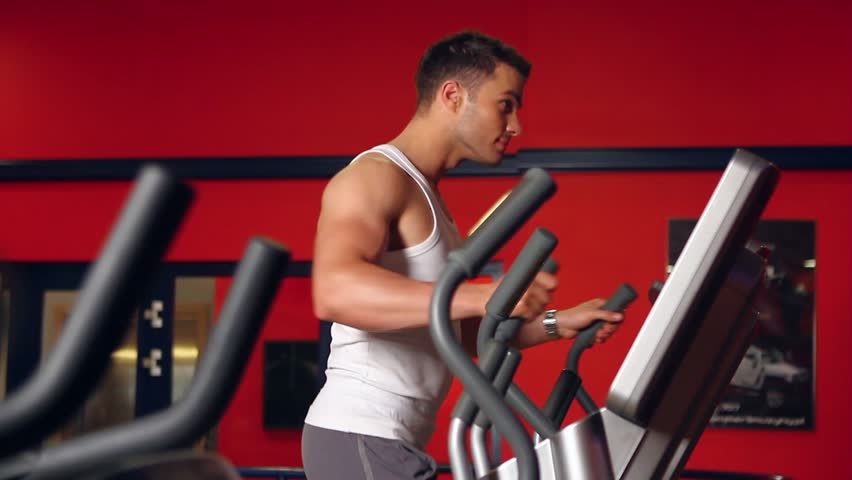 Handsome sporty man is exercising in gym centre