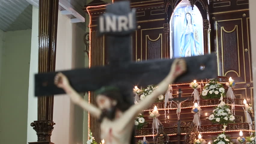 statue of the crucified Jesus Christ in the church with candles on the background