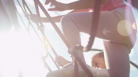 Two young girls climbing on a rope climbing frame on a sunny day in slow motion, shot on RED EPIC