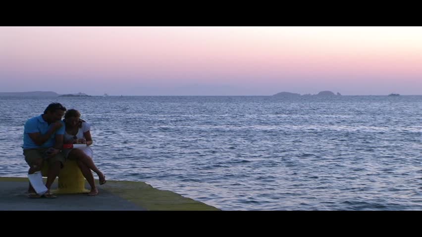 A couple sitting on port waiting under the sunset