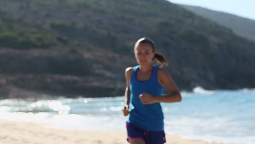 Beautiful brunette female athlete relaxing tired after jogging exercise training outdoors, slow motion