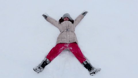 Young girl making a snow angel. Slow motion, high speed camera