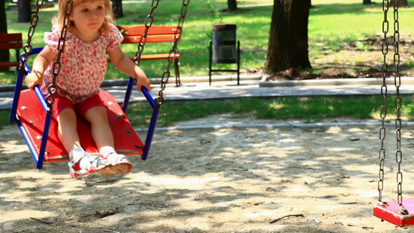 Child rides a swing in the park.