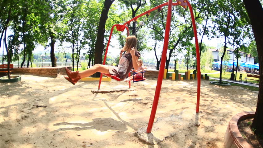 Child and his mother ride on a swing. Camera flies. 