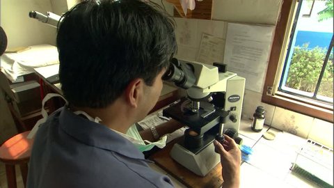 Scientist looking at samples under a microscope at tuberculosis lab in Lima, Peru,