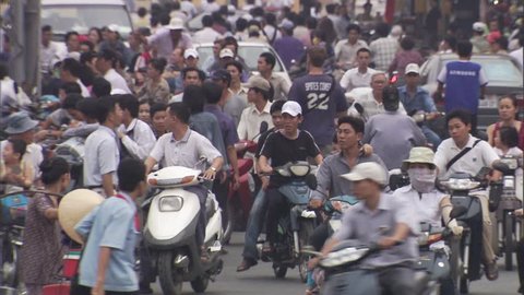 Automobiles and riders on scooters at busy intersection in Ho Chi Minh City, Vietnam,