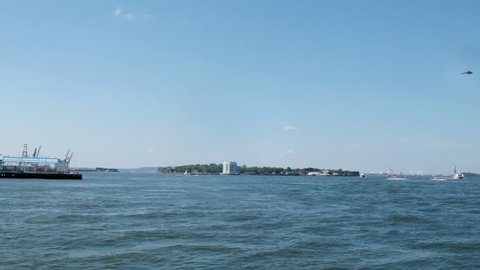 Boat floats on sea near the city and the statue of liberty. Time lapse.