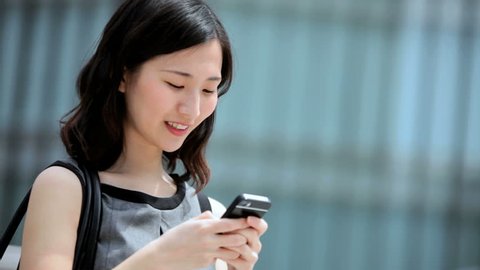 Ambitious ethnic Asian Japanese girl advertising business outdoors downtown buildings wireless hotspot smart phone connection స్టాక్ వీడియో