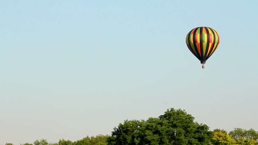 A hot air balloon gently glides through the air on a summer evening.