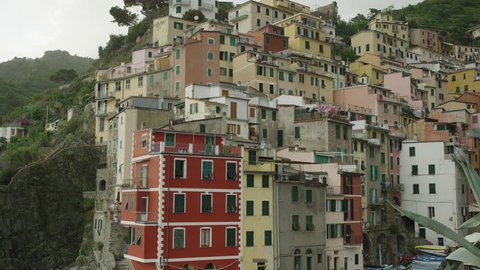 Slow motion panning shot of village built on hillside / Riomaggiore, Cinque Terre, Italy