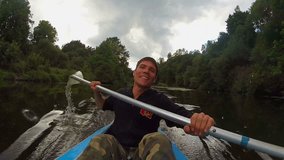Young positive man paddling kayak, action camera, active rest