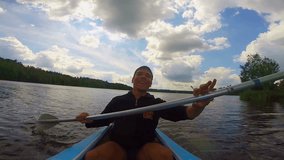 Young happy man actively paddling kayak, singing. Action camera