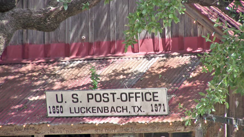 Video zoom out of Luckenbach Texas made famous by Waylon Jennings song. Post office with three residents. Large oak trees and now a dance hall and tourist area under a large oak tree. 
