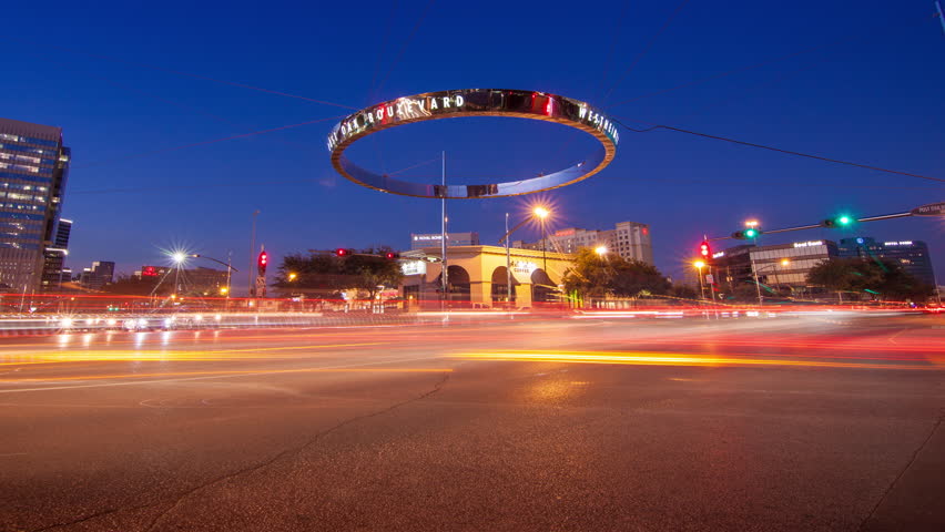 HOUSTON TX - 2014: Galleria Timelapse of Traffic during Sunset at Westheimer and Post Oak Boulevard Intersection with Fast Moving Lights on a Vibrant Colored Texas Evening