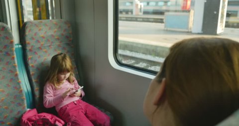 Cute little girl play a game with phone in her hand, while waiting for the train departure
