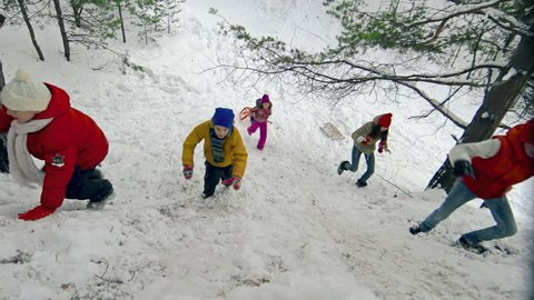 Right from above view of five jolly children climbing up the snowy hill