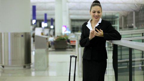 Female Caucasian brunette businesswoman consultant airport departures hall travel destination professional wireless smart phone technology communication