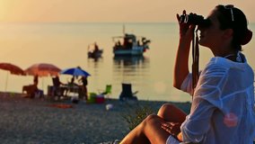 Girl with binoculars at the beach ; Young woman with binoculars watching a beautiful sunset on the beach of the Mediterranen Sea,video clip