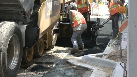 MIAMI - OCTOBER 2010 - Construction workers next to an asphalt finisher laying down a fresh layer of asphalt.