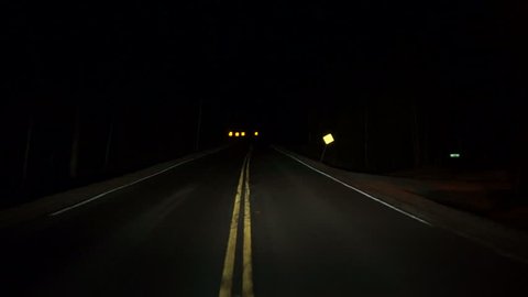Driving down a twisting and turning dark rural highway at night timelapse. 