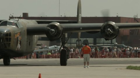 BELLEVILLE, MI, USA – AUGUST 2014: Crew member helps as B-24 Liberatorl bomber plane from World War II turns off engines and parks at an air show.  Recorded in 4K, ultra high definition.