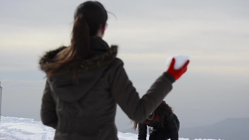 Two teen friends having fun fighting with snowball on snow