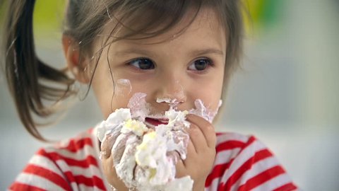 Close up of adorable little girl devouring cake with her hands