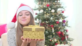 Surprised Young Beauty girl in Santa's hat opens Christmas gift box. Christmas and New Year tree. Amazed Happy woman with magic gift. HD video footage 1080