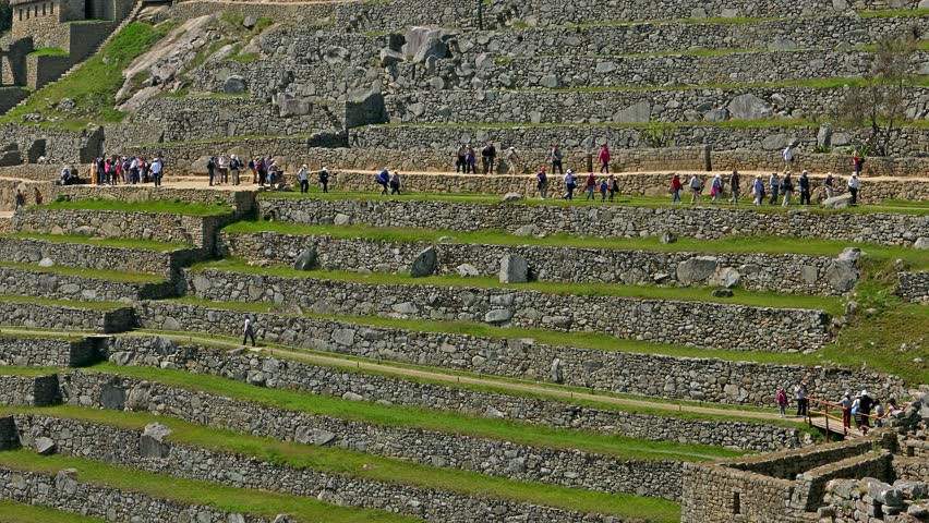 Terraces of Machu Picchu with tourists crossing the scene