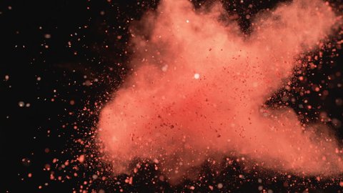Red powder/particles fly after being exploded against black background. Shot with high speed camera, phantom flex 4K. 4K 30fps. Slow Motion.