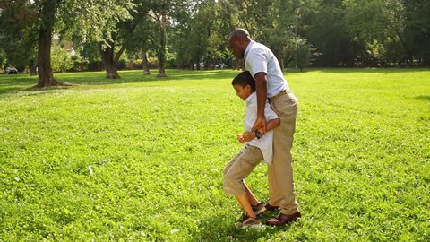 Father and son playing in the summer park, father spins son